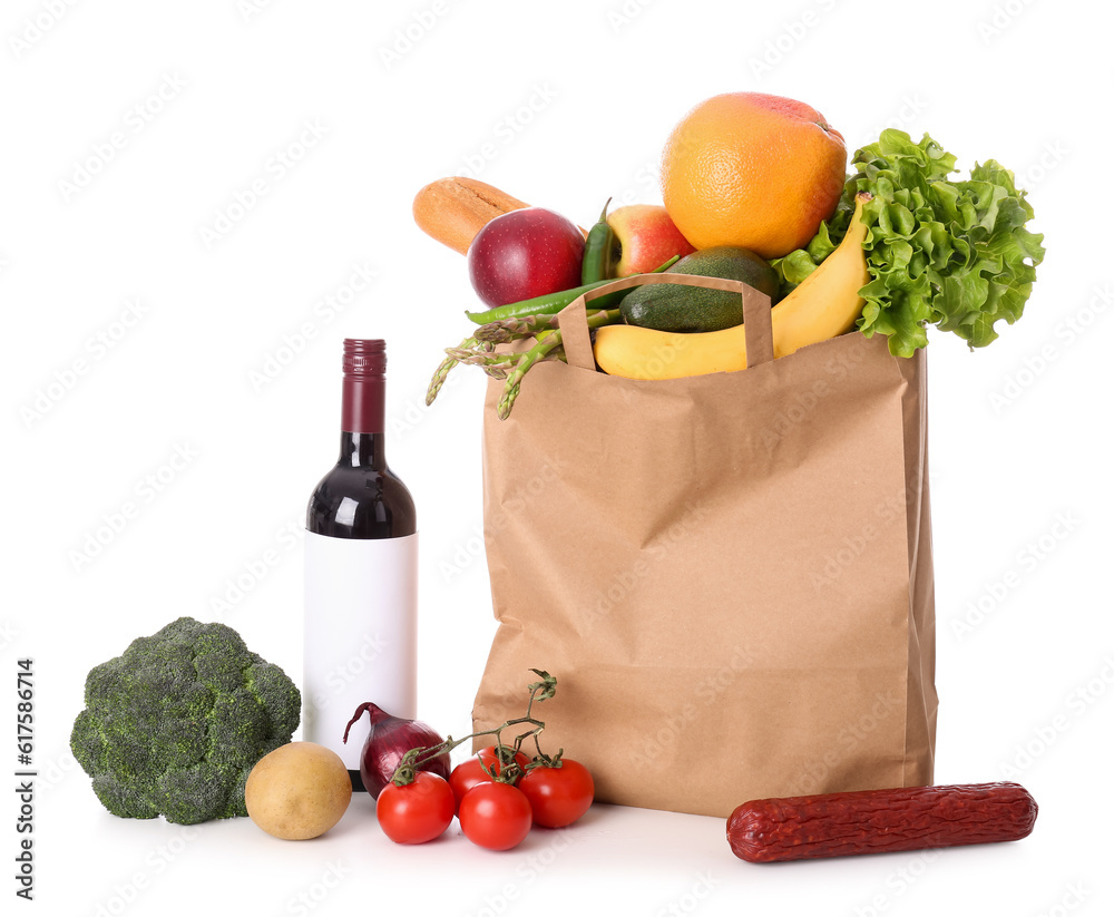 Paper bag with vegetables, fruits and wine bottle on white background