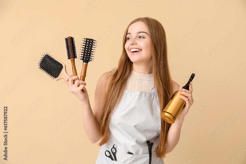 Female hairdresser with brushes and spray on beige background