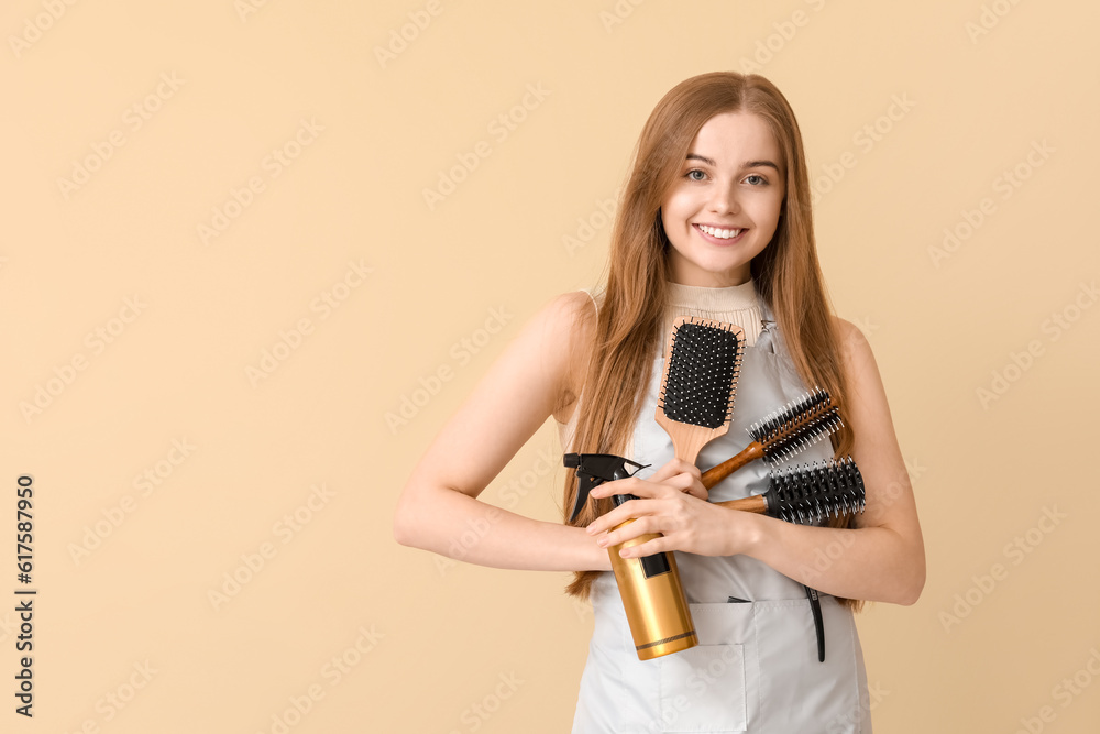 Female hairdresser with brushes and spray on beige background