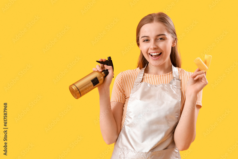 Female hairdresser with spray and curlers on yellow background