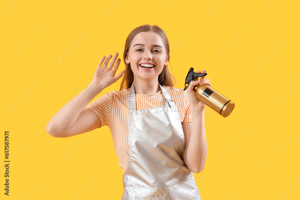 Female hairdresser with spray on yellow background