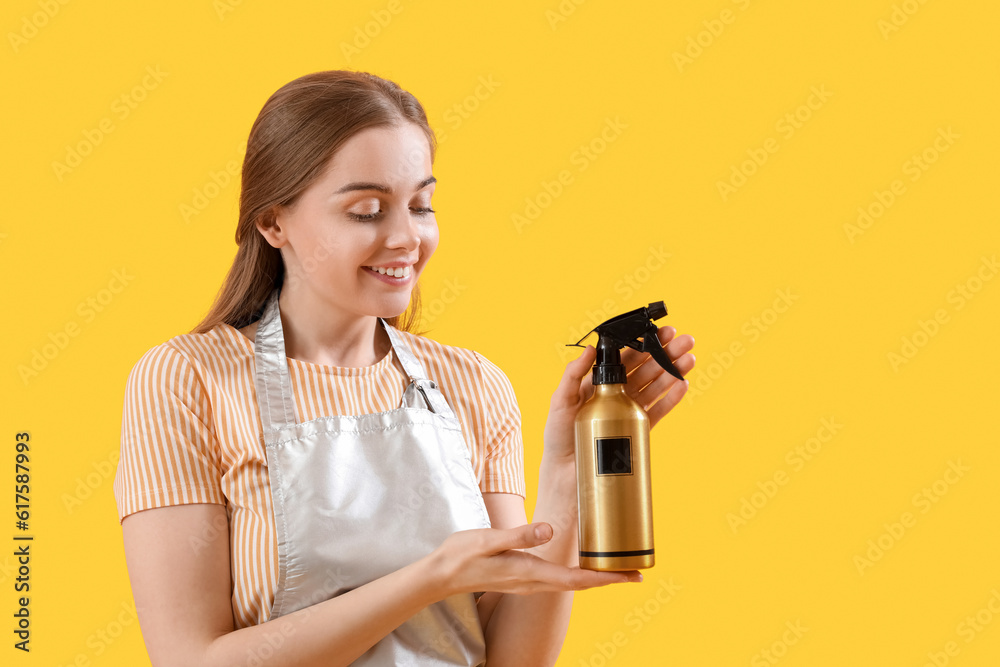 Female hairdresser with spray on yellow background