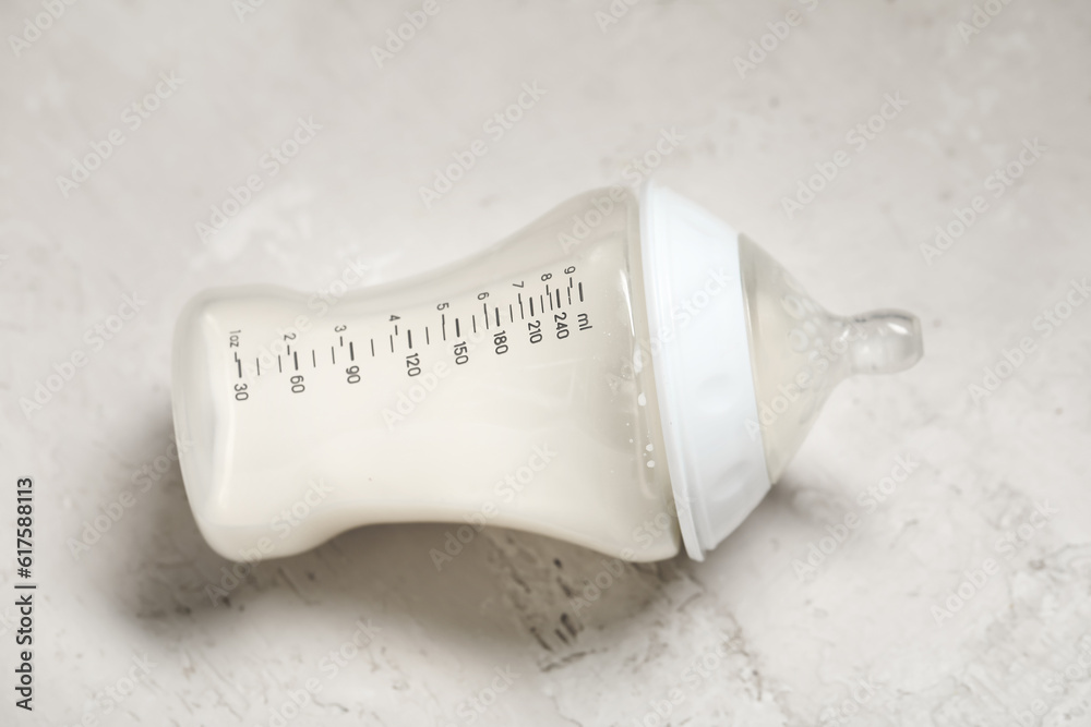 Bottle of milk for baby on white textured background