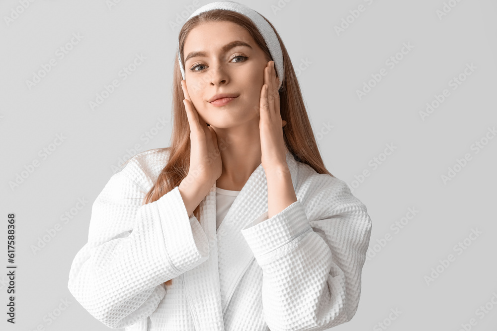 Young woman doing face building exercise on light background