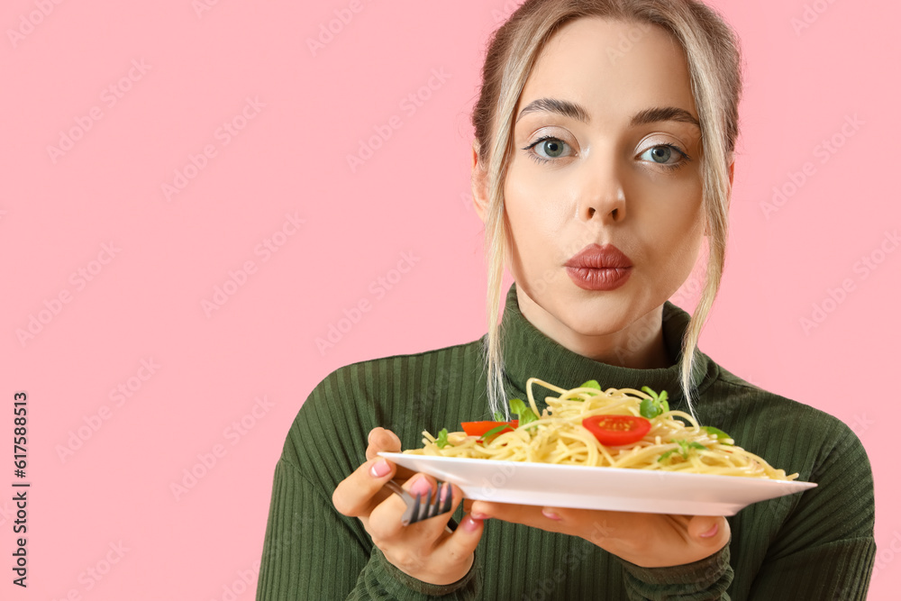 Young woman with tasty pasta on pink background, closeup