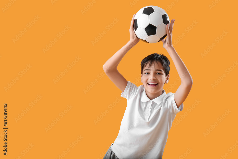 Little boy with soccer ball on yellow background