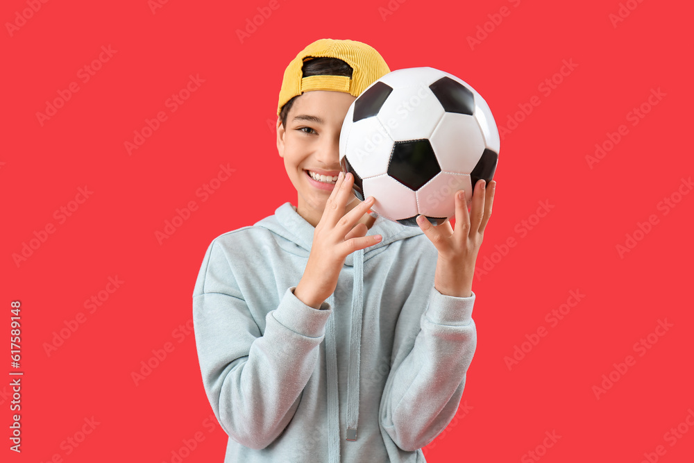 Little boy with soccer ball on red background