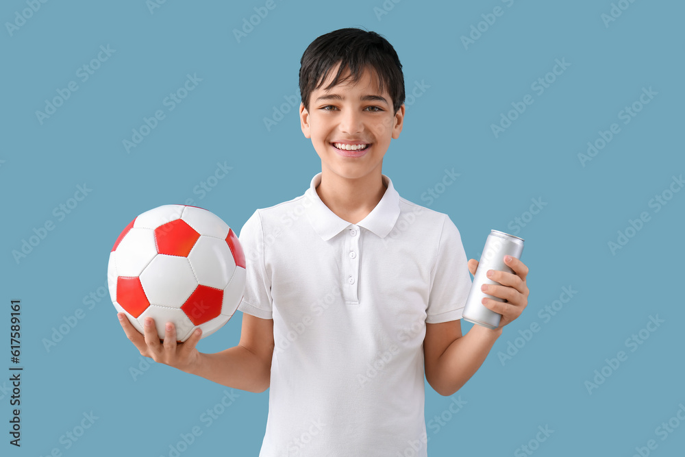 Little boy with soccer ball and soda on blue background