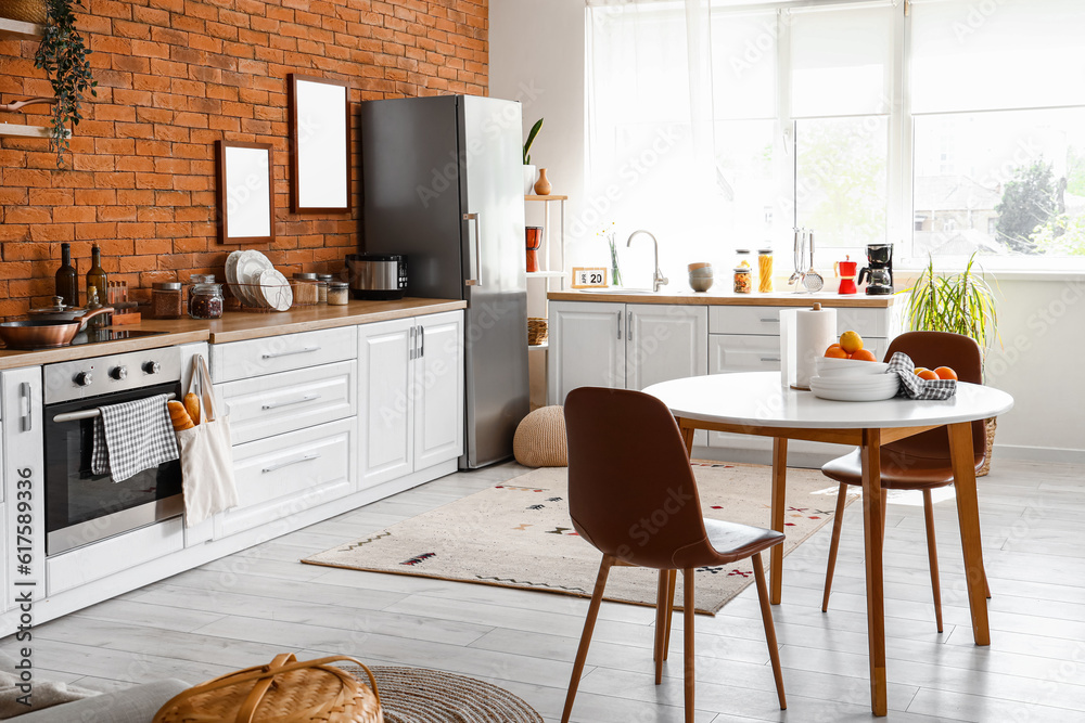 Interior of kitchen with stylish fridge, counters, table and chairs