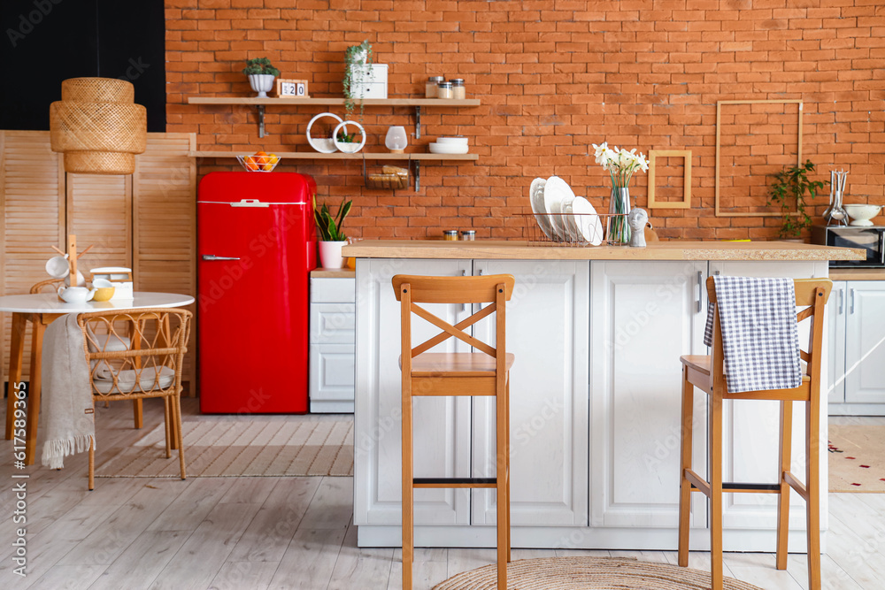 Interior of kitchen with red fridge, counters, shelves and chairs