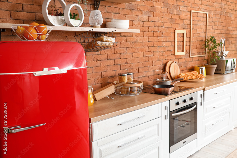 Interior of kitchen with red fridge, counters, shelf and utensils