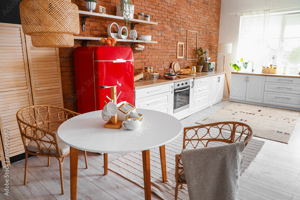 Interior of kitchen with red fridge, counters, shelves, table and chairs