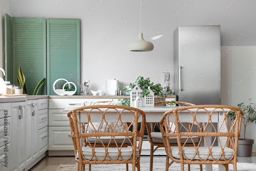 Interior of light kitchen with stylish fridge, counters, table and chairs