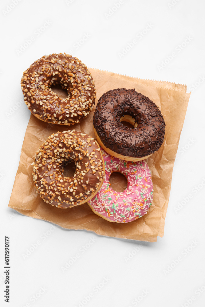 Paper bag with sweet donuts on white background