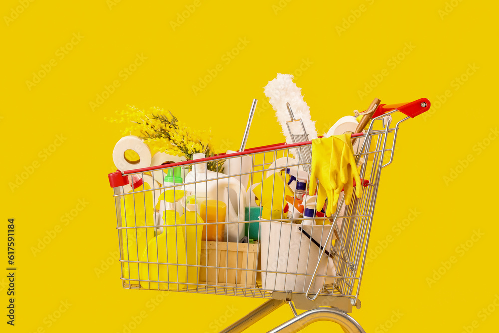 Shopping cart full of cleaning supplies with flowers on yellow background