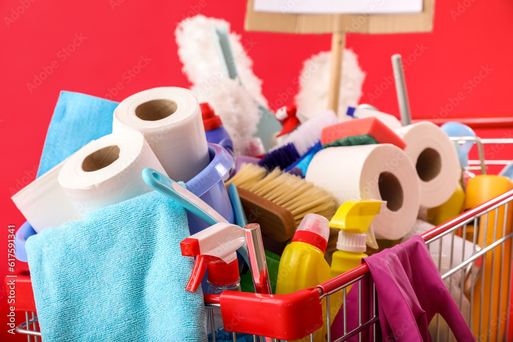 Shopping cart full of cleaning supplies on red background