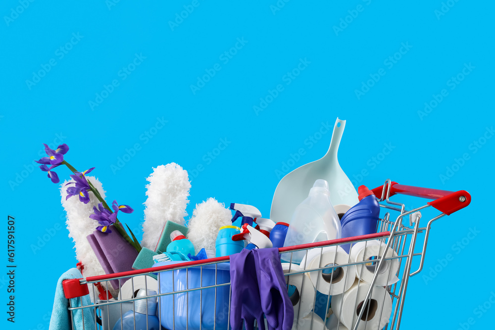 Shopping cart full of cleaning supplies and purple flowers on blue background