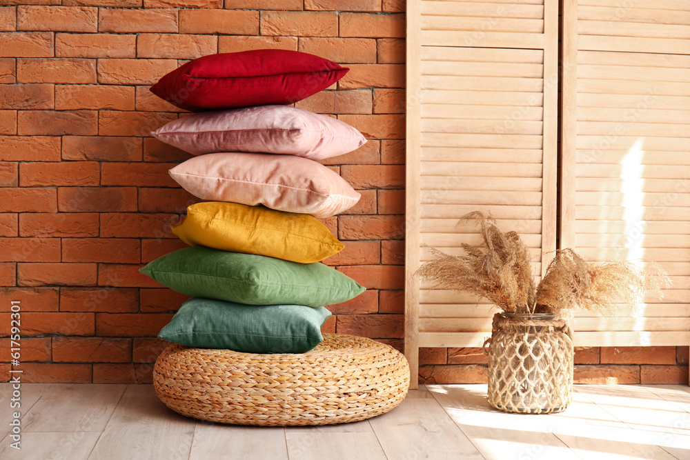 Stylish pillows on pouf and vase with pampas grass in room