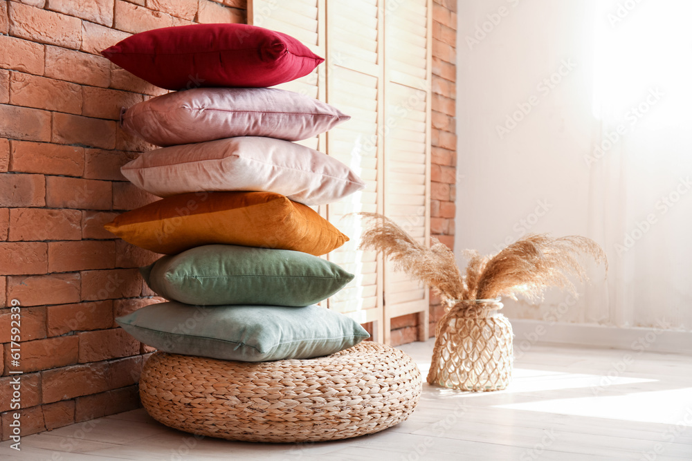 Stylish pillows on pouf and vase with pampas grass in room