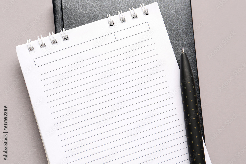 Notebooks and pen on grey background, closeup