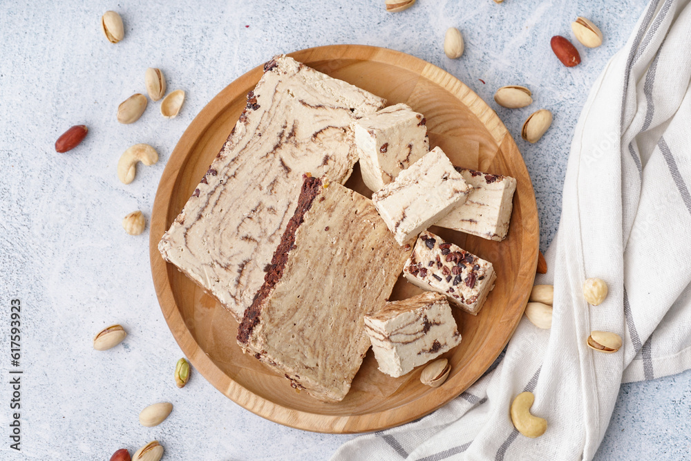 Plate with pieces of tasty marble halva on light background