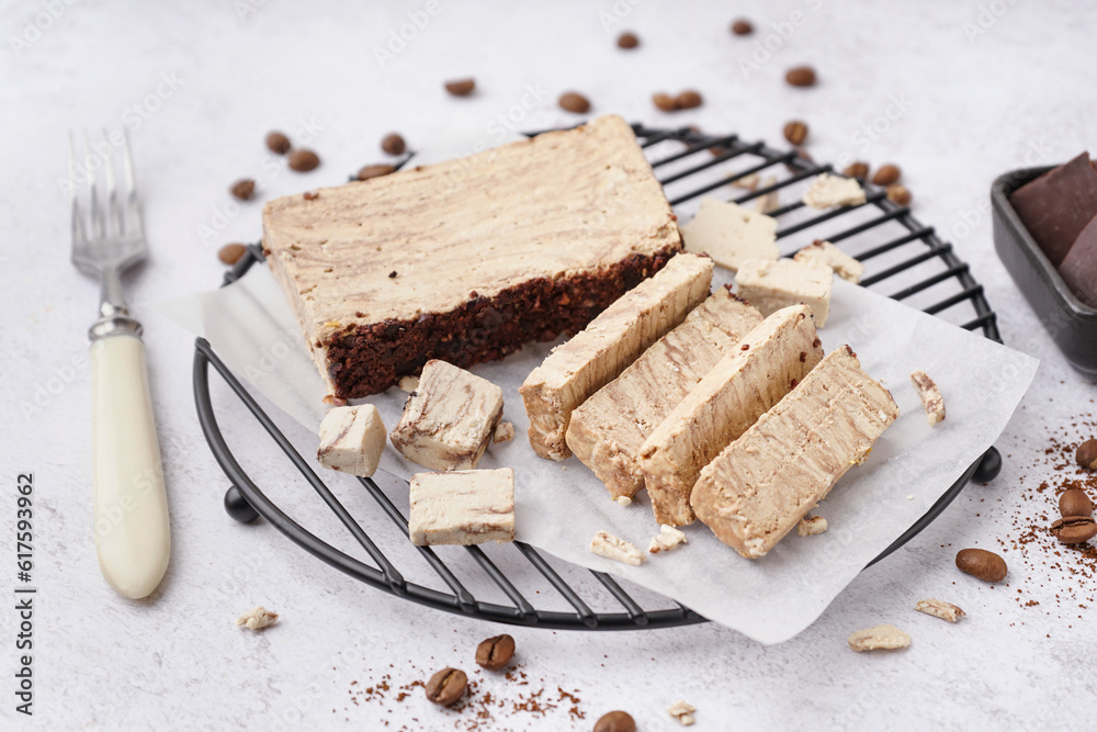 Grid with pieces of tasty marble halva on light background