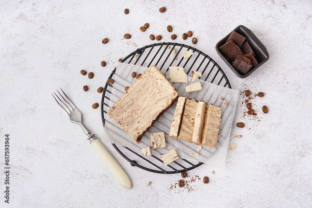 Grid with pieces of tasty marble halva on light background