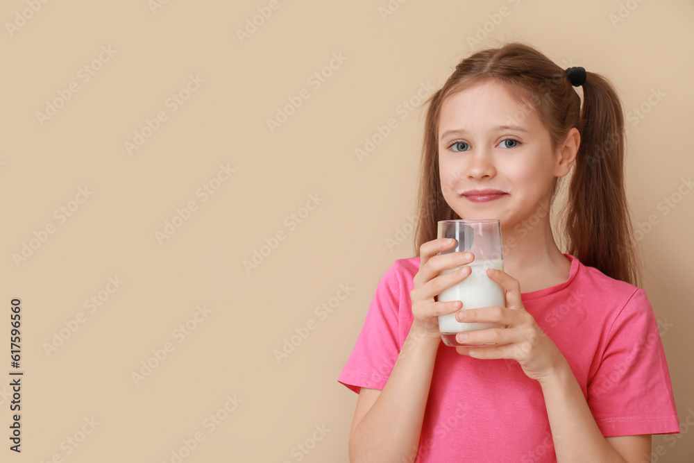 Little girl with glass of milk on beige background