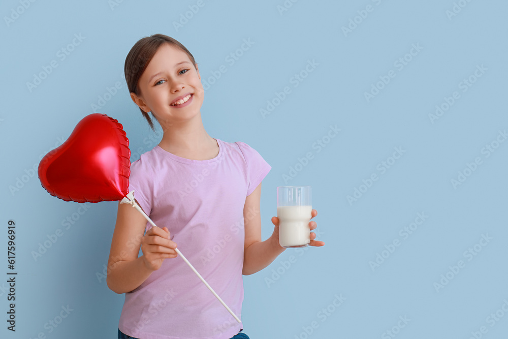 Little girl with glass of milk and balloon on light blue background