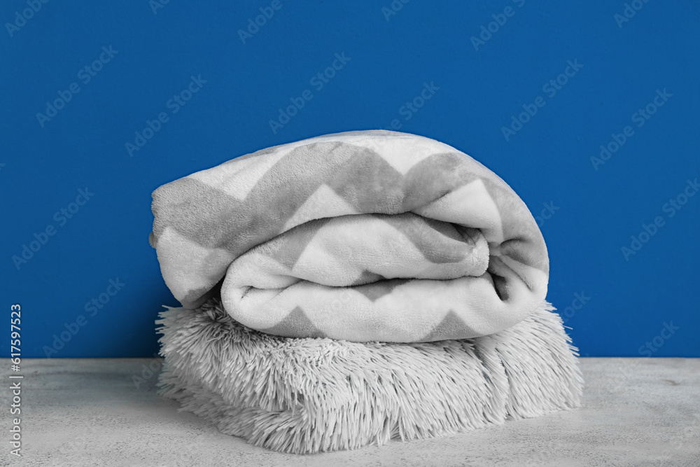 New soft folded blankets near blue wall