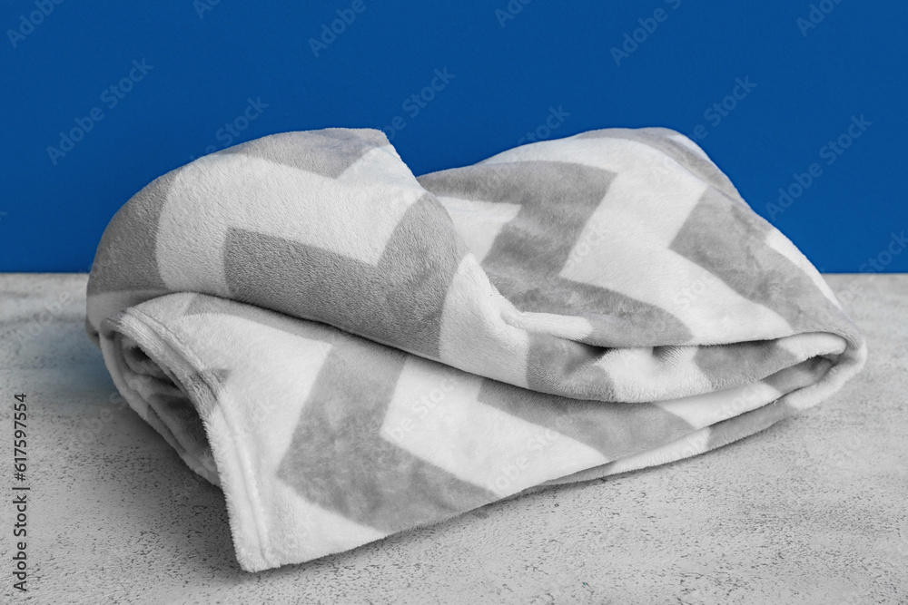 New soft folded blanket near blue wall