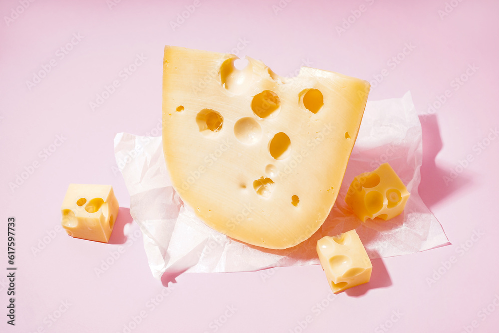 Baking paper with pieces of Swiss cheese on pink background