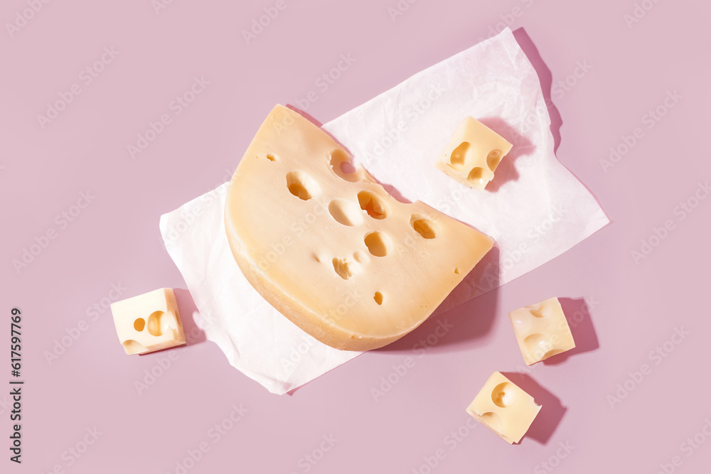 Baking paper with pieces of Swiss cheese on pink background