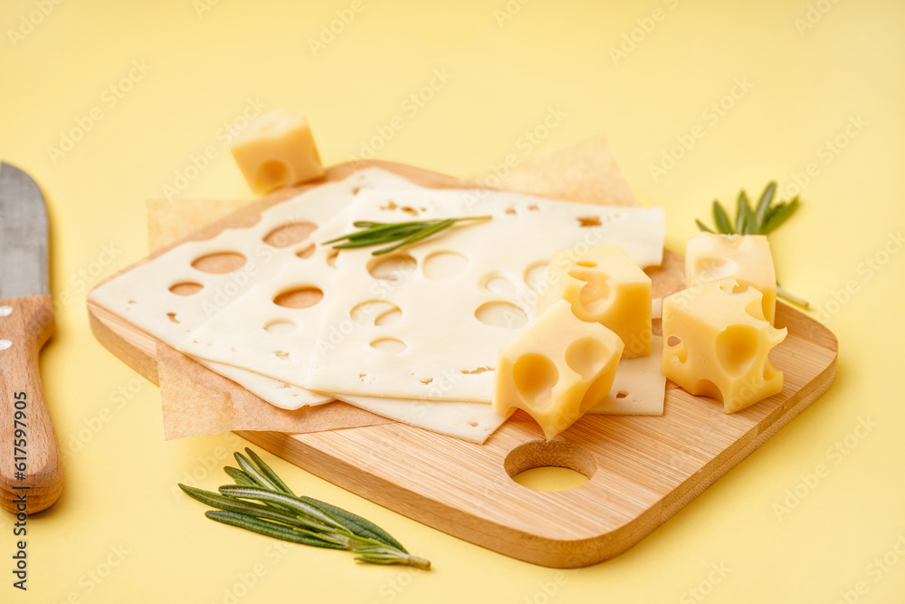 Board with pieces of Swiss cheese on yellow background