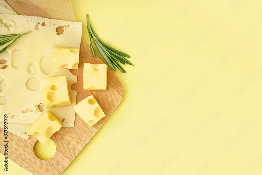 Board with pieces of Swiss cheese on yellow background