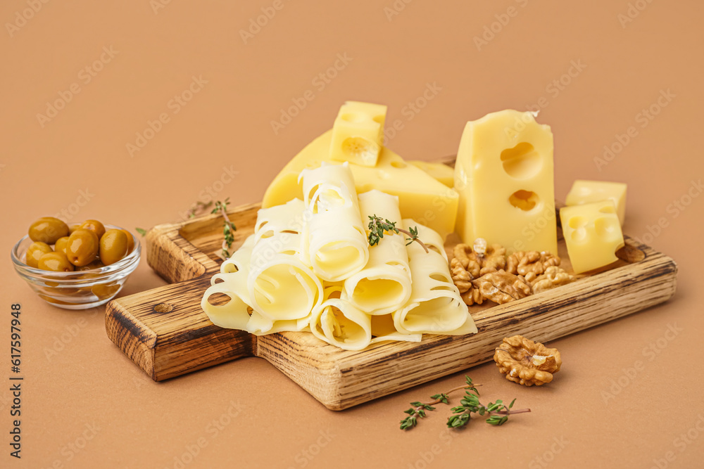 Board with pieces of Swiss cheese and walnut on brown background