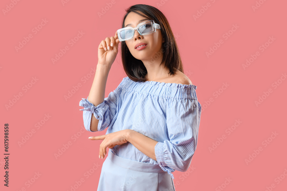 Beautiful Asian woman in stylish sunglasses on pink background