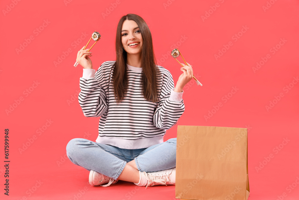 Young woman with sushi and paper bag sitting on red background