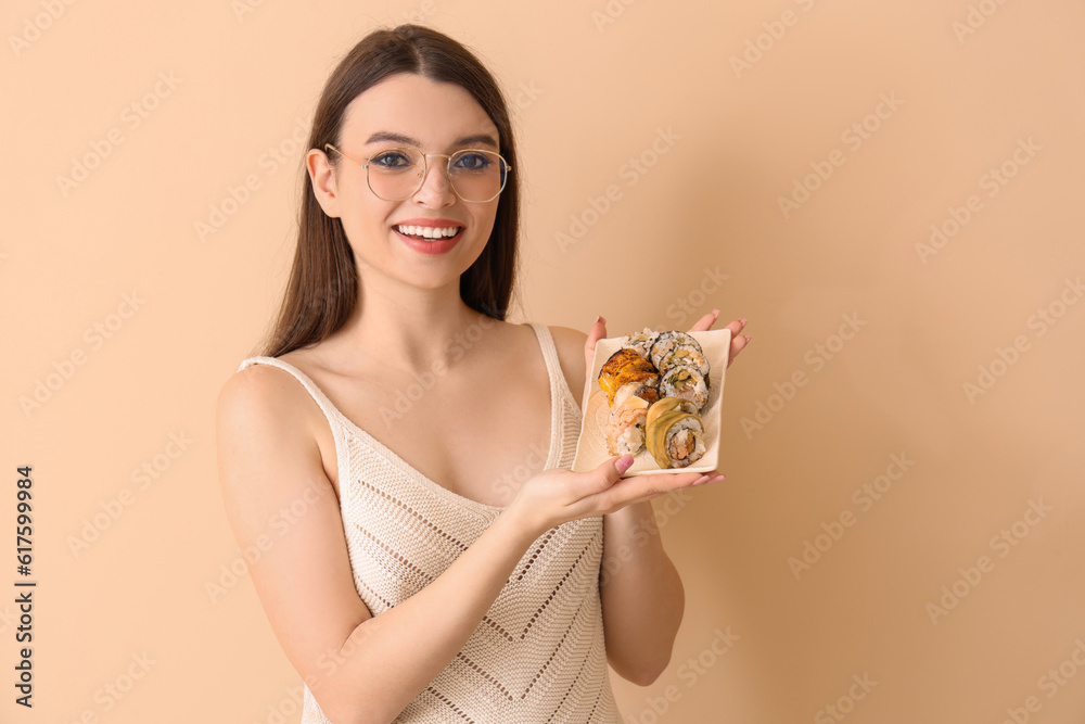 Young woman with sushi on beige background