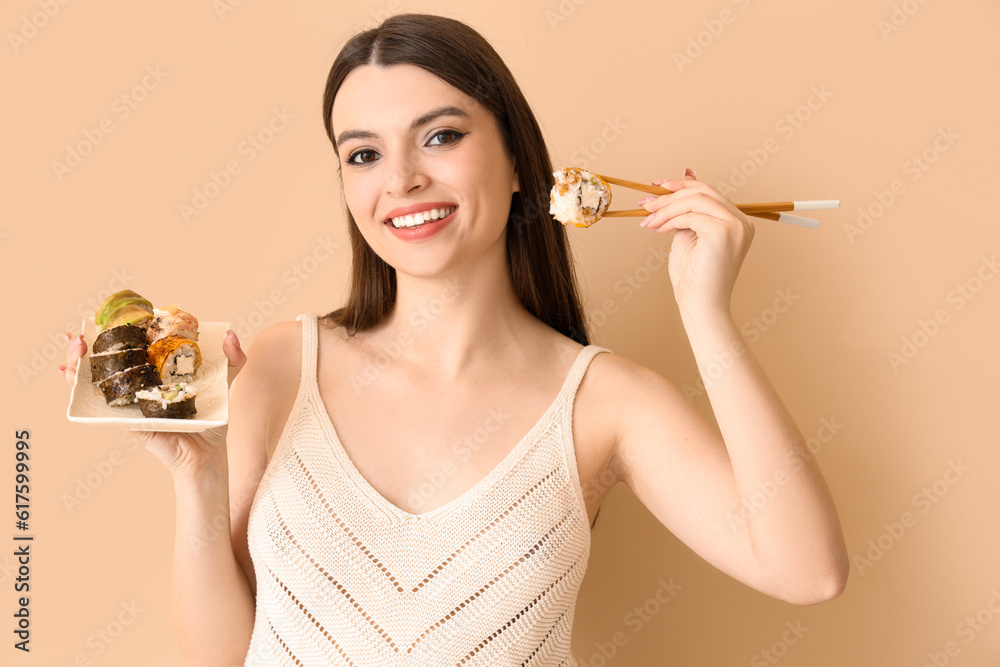 Young woman with sushi on beige background