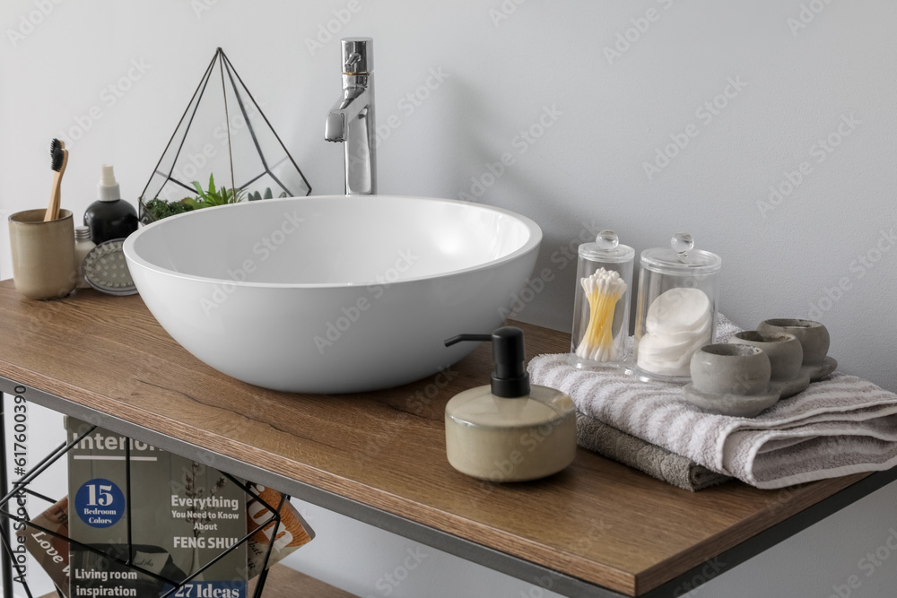 Table with sink bowl, soap dispenser and bath accessories in bathroom