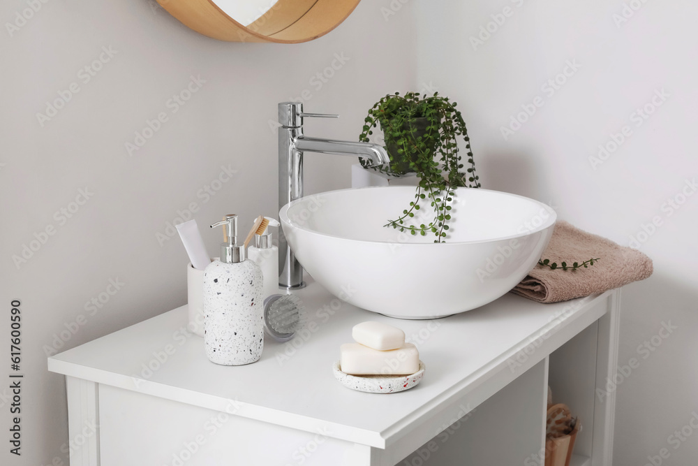 Sink bowl, soap bars, dispensers and bath accessories on table in bathroom