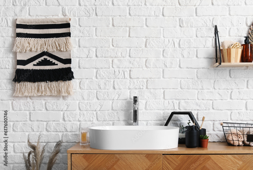 Sink bowl and bath accessories on wooden cabinet in bathroom