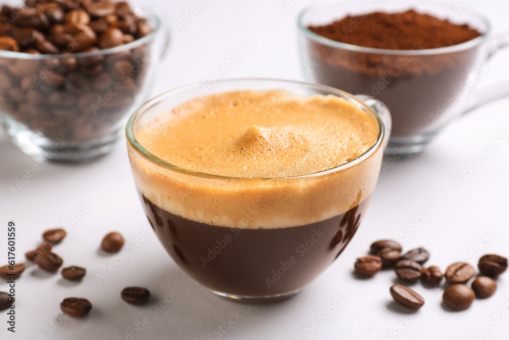 Cups of hot espresso and coffee beans on white background