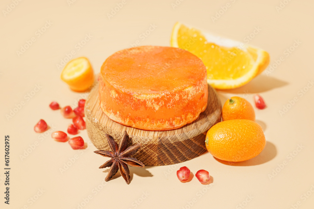 Wooden stand with solid shampoo bar with orange, kumquat and pomegranate on beige background