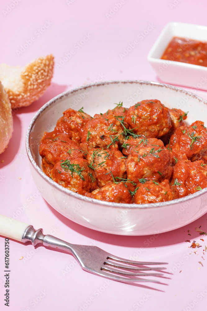 Bowl of tasty meat balls with sauce on pink background