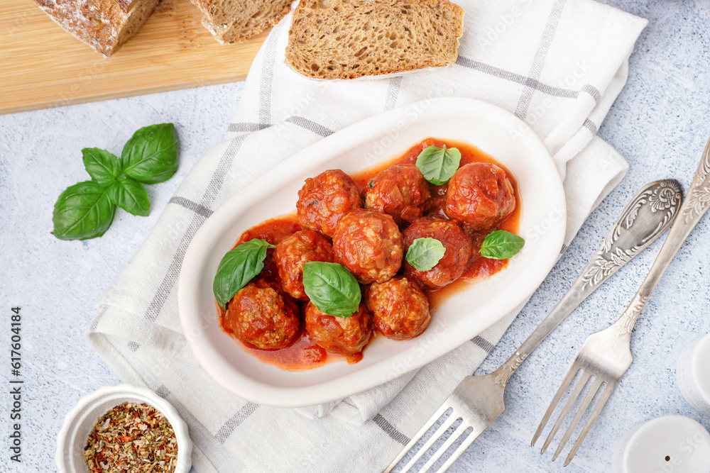 Plate of tasty meat balls with tomato sauce and basil on grey table