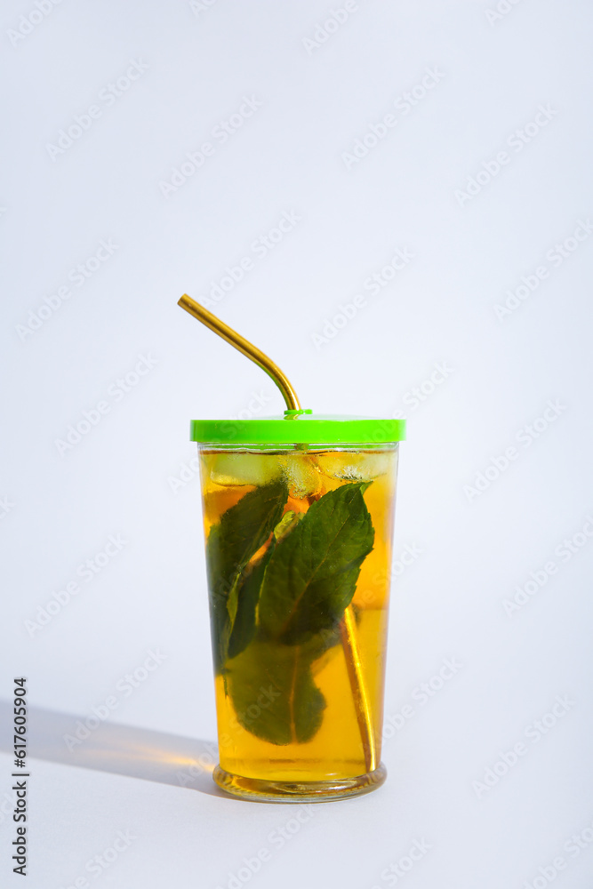 Glass of ice tea with mint and lemon on white background