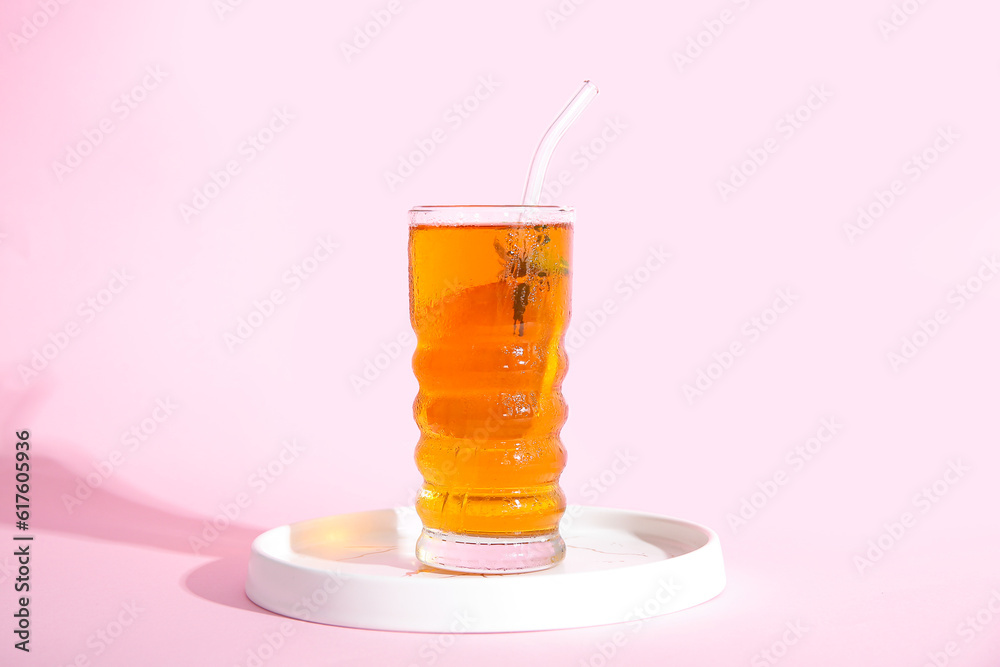 Glass of ice tea with orange on pink background