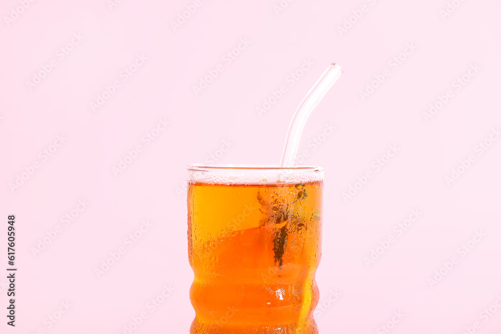 Glass of ice tea with orange on pink background